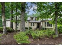 Charming home featuring a tan stucco exterior, complemented by mature trees and lush landscaping at 3261 Stonecreek Ct, Suwanee, GA 30024