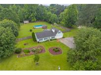 Aerial view of a light green home with a large yard and inground pool surrounded by mature trees at 1789 Brandi Ln, Loganville, GA 30052