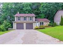 Charming two-story home featuring a two-car garage and well-manicured front lawn surrounded by lush greenery at 765 Martin Rd, Stone Mountain, GA 30088