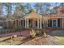 Charming brick home featuring a welcoming front porch with white columns and shuttered windows at 200 Mcguirts Bridge Rd, Covington, GA 30014