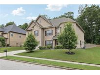 Charming two-story home featuring a well-manicured lawn, lush trees, and a welcoming driveway at 3748 Spring Place Ct, Loganville, GA 30052