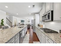 Modern kitchen boasts granite countertops, stainless steel appliances, and a seamless open-concept design to the living room at 3748 Spring Place Ct, Loganville, GA 30052