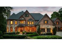Elegant brick and stone exterior with manicured landscaping, a large front door and a three-car garage at 3155 Wills Mill Rd, Cumming, GA 30041