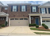 Townhome exterior with brick facade, black shutters, a two-car garage, and manicured landscaping at 209 Ellis Ln, Woodstock, GA 30189
