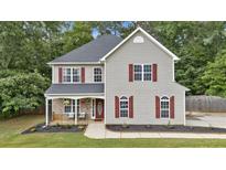 Charming two-story home featuring red shutters, a covered porch, and professionally landscaped front yard at 6350 Summer Pl, Douglasville, GA 30135