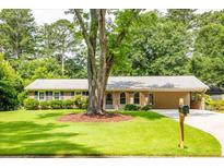 Charming single-story home featuring a well-manicured lawn and mature trees, complemented by a welcoming facade at 4150 Glenn St, Powder Springs, GA 30127