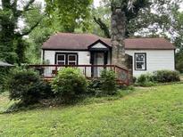 Charming one-story home featuring a front deck, stone chimney, and verdant landscaping at 2463 Stone Rd, East Point, GA 30344