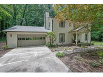 Charming two-story home with a well-manicured front yard, attached garage, and a serene setting surrounded by lush trees at 82 Vanessa Se Dr, Smyrna, GA 30082