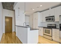 This kitchen has white cabinets, stainless steel appliances, granite countertops, and hardwood floors at 943 Peachtree Ne St # 716, Atlanta, GA 30309