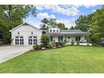 Charming home with a well-manicured lawn and a two-car garage, nestled under a beautiful blue sky at 221 Brooke Dr., Alpharetta, GA 30009