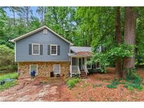 Two-story home with blue siding and stone base, surrounded by lush greenery at 4585 Muirwood Cir, Powder Springs, GA 30127