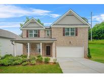 Charming two-story brick home with a well-manicured lawn, attached garage, and inviting covered front porch at 603 River Gardens Se Dr, Atlanta, GA 30354