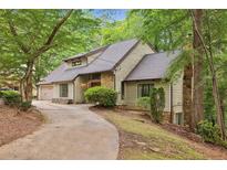 Charming home featuring stone accents, driveway, lush landscaping, and an attached garage nestled amongst mature trees at 6100 Blackwater Trl, Atlanta, GA 30328