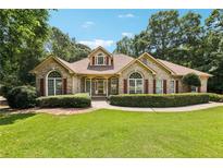 Charming brick home with a lush lawn, beautiful landscaping, and red window shutters under a sunny blue sky at 8110 Lakemont Close, Mcdonough, GA 30253