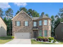 Charming two-story brick home with a manicured lawn, attached garage, and mature trees at 10137 Cormac St, Jonesboro, GA 30238
