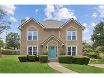 Two story home with a landscaped yard and a bright teal front door on a sunny day at 1850 Thomas Ne Dr, Marietta, GA 30066