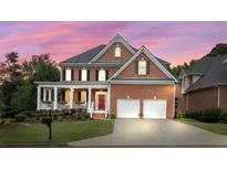 Charming two-story brick home with a covered front porch, two-car garage, and landscaped yard at sunset at 1140 Promontory Drive, Marietta, GA 30062