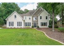 Two-story stucco home with stone accents, manicured lawn, and lush green landscaping at 2970 Chardonnay Ln, Cumming, GA 30041