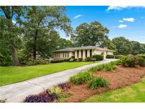 Beautiful single-story home with a sprawling lawn and mature trees, creating a serene and inviting landscape at 322 Emily Drive Sw, Lilburn, GA 30047
