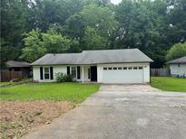 Quaint, single-story home featuring a two-car garage and dark black shutters against a white exterior at 8249 Creekline Ct, Riverdale, GA 30274