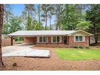 Charming brick home featuring a covered carport and well-maintained front yard with mature trees at 2695 Peeler Rd, Dunwoody, GA 30360
