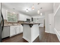 Bright kitchen with white cabinets, island, stainless steel appliances, and modern lighting at 1086 Erie Cir, Stone Mountain, GA 30087