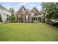 Charming two-story brick home with a well-manicured lawn, mature trees, and a welcoming front porch at 4320 Cody Ct, Cumming, GA 30040