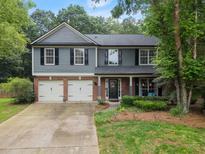 Charming two-story home with a well-manicured lawn, attached garage, and welcoming front porch at 5885 Millstone Dr, Cumming, GA 30028