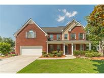 Two-story red brick home featuring a well-manicured lawn and beautiful landscaping at 2479 Mitford Ct, Dacula, GA 30019