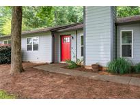 Charming single-story home showcasing a gray facade, bright red front door, and beautifully landscaped surroundings at 609 Hearth Pl, Lawrenceville, GA 30043