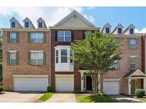 Three-story brick townhome with a two-car garage and front door at 5126 Wellsley Bnd, Alpharetta, GA 30005