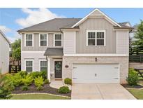 Charming two-story home featuring a brick and siding facade, complemented by a well-maintained front yard and a two car garage at 306 Coppergate Ct, Holly Springs, GA 30115