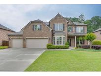 Beautiful brick two-story home featuring a three car garage and lush, well-manicured front lawn at 470 Wagon Hill Ln, Sugar Hill, GA 30518