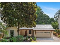 Charming home featuring a well-manicured lawn, a wooden garage door, and a canopy of lush trees at 407 Westside Dr, Roswell, GA 30075