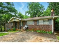 Charming brick home with a cozy front porch and mature trees, showcasing its curb appeal and inviting atmosphere at 6126 Knights Ln, Douglasville, GA 30135