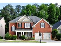 Charming two-story red brick home with a manicured lawn, inviting front porch, and a two-car garage at 1951 Barrett Knoll Nw Cir, Kennesaw, GA 30152