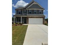 Two-story home boasts stone accents, a neutral color palette, an attached two car garage, and well manicured front lawn at 324 Bloomfield Cir, Canton, GA 30114