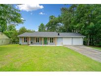 Charming single-story home with a well-manicured lawn, attached garage, and inviting front porch at 130 Sunnybrook Ln, Woodstock, GA 30188