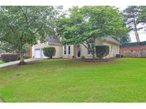 Charming home with lush green lawn and mature trees offering shade and curb appeal at 2230 Laurel Lake Dr, Suwanee, GA 30024