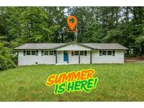 Charming ranch style home with freshly painted white exterior, blue door, and spacious front yard with mature trees at 2091 Chestnut Log Dr, Lithia Springs, GA 30122