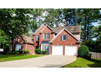 Beautiful brick home with a well-manicured lawn, mature trees, and two-car garage at 2720 Stillwater Lake Ln, Marietta, GA 30066