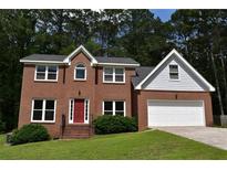 Charming two-story brick home with a well-manicured lawn and a two-car garage, nestled among mature trees at 1471 Ashwood Way, Lawrenceville, GA 30043