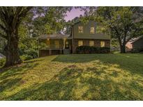 Charming two-story home featuring brick accents and a welcoming covered porch with beautiful landscaping and mature trees at 4819 Elam Rd, Stone Mountain, GA 30083