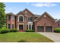 Elegant two-story red brick home featuring a well-manicured lawn and attached two-car garage at 141 Ennisbrook Se Dr, Smyrna, GA 30082