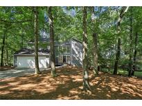 Charming two-story home with a gray exterior and a two-car garage nestled in a wooded lot at 545 Woodman Pl, Roswell, GA 30076