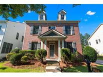 Charming brick home featuring dormer windows, shutters, and a well-manicured front yard at 1666 Baxley Pine Trce, Suwanee, GA 30024