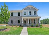 Charming two-story home featuring a brick facade, covered porch, and lush green lawn, perfect for Gathering living at 1716 Hickory Heights (Lot 2) Way, Acworth, GA 30102