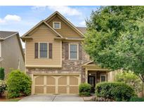 Charming two-story home with stone accents, a two-car garage and well-maintained landscaping at 8360 Village School Dr, Cumming, GA 30041