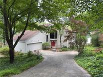 Inviting home featuring a red front door, two car garage and mature trees enhancing the curb appeal at 3836 Loch Highland Ne Pkwy, Roswell, GA 30075