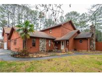 Charming wood home featuring stone accents, a stone chimney, a front porch, and mature trees at 4800 Silverberry Nw Ln, Acworth, GA 30102